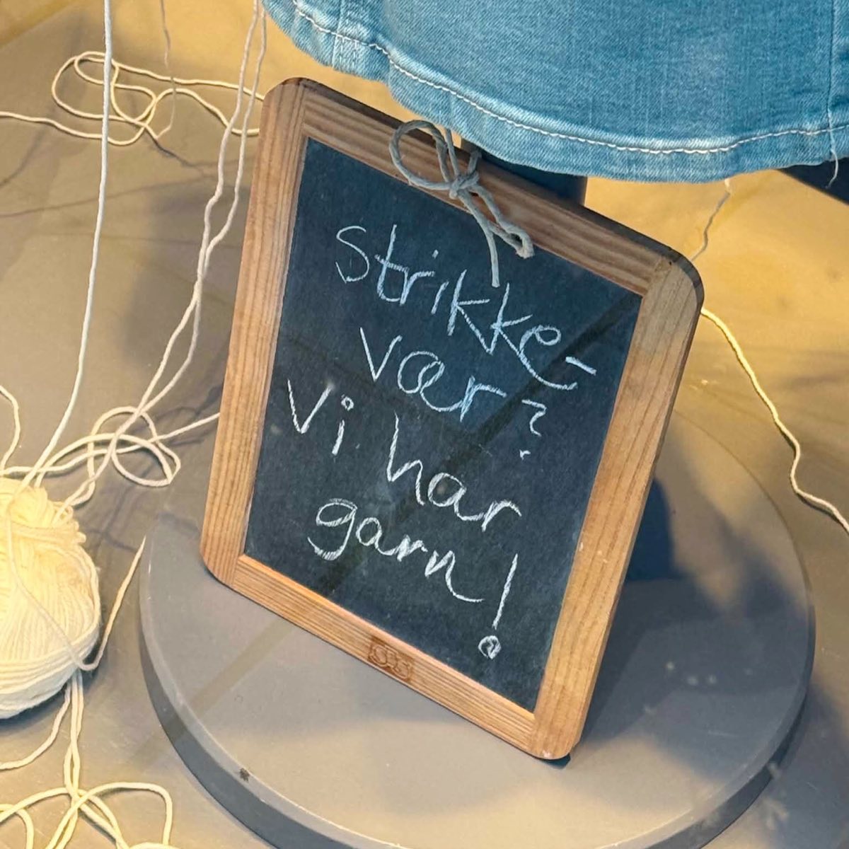 Liten tavle i vinduet med teksten «Strikkevær? Vi har garn!»